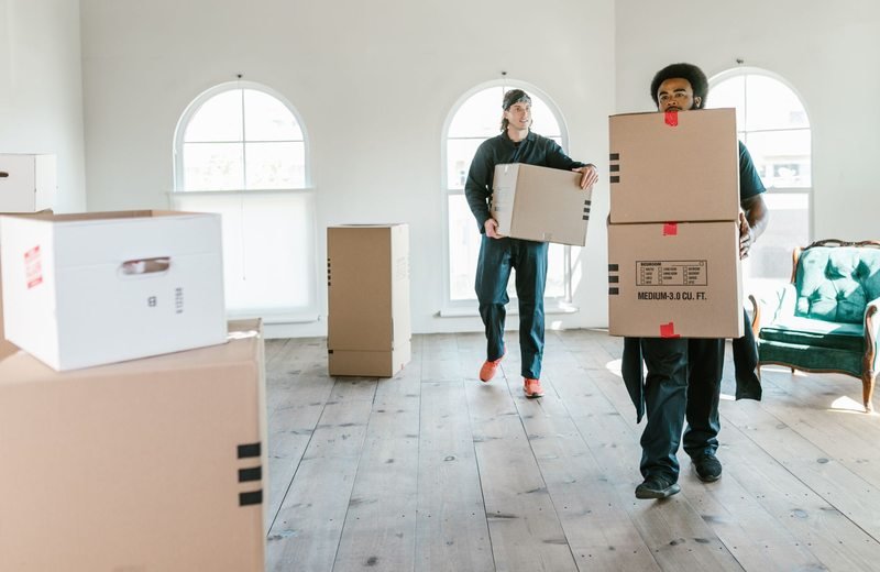 Workers carrying cardboard boxes inside a residence